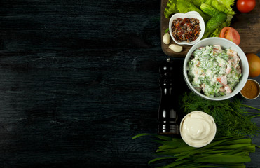 Salad with vegetables. View from above. Fresh salad in a plate on a dark background. Garlic, tomato, cucumber, dill and onion in a dish of dark surface. Copy space.