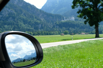 Landscape view in the rear view mirror. Breathtaking Tannheim Mountains and countryside near Schwangau. Road trip and fairy tale scenery along the Romantic Road, Germany's oldest holiday route.