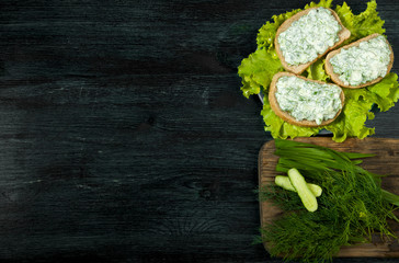 Sandwiches with vegetables. Fresh sandwiches with vegetables on a dark board on a textured background. View from above. Copy space