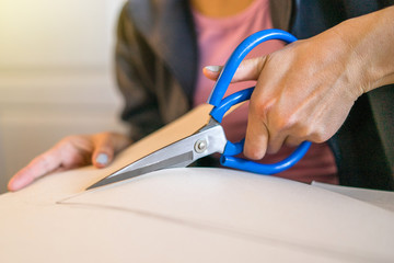 Close up on hands holding paper cardboard cutting using scissors at home office