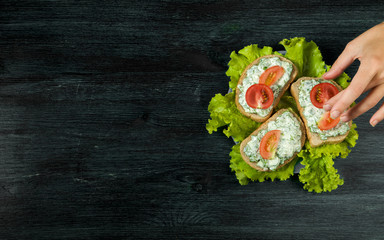 Sandwiches with vegetables. Fresh sandwiches with vegetables on a dark board on a textured background. View from above. Copy space