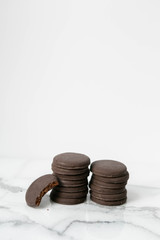 Stack of thin mints cookies on white marble background, chocolate mint thin round cookies