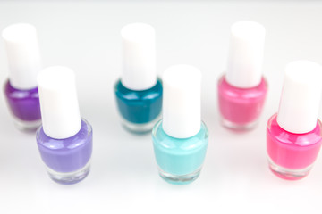 Group of bright multicolor nail polishes in a raw with reflection on a white table