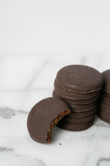 Stack of thin mints cookies on white marble background, chocolate mint thin round cookies
