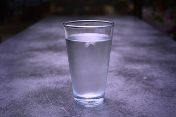 Glass of water placed on table with tiny droplets of condensation.