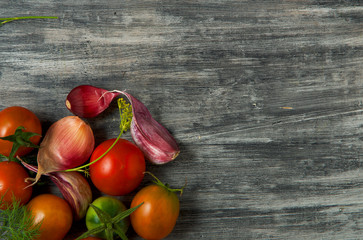 Tomatoes on the background. Tomatoes, garlic on a wooden surface. View from above. Fresh vegetables. copy space.