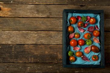 Tomatoes on the background. Tomatoes, garlic on a wooden surface. View from above. Fresh vegetables. copy space.