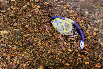 stone beach background and snorkeling equipment mask and tube 