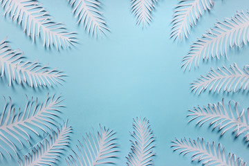 Paper handmade feathers leaves arranged in a circle on blue bacground. Photo with copy blank space.