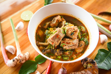 Pork rib curry spicy soup / pork bone with hot and sour soup bowl with fresh vegetables Tom Yum thai herbs and spices ingredients with chilli lemon on wooden background Thai Food Asian