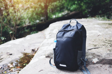 Backpack on nature with bottle for backpacker hiker on the rock in the forest on mountain