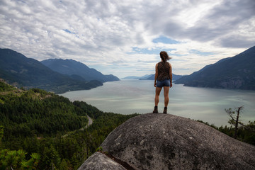 Obraz premium Adventurous Girl Hiking up a mountain during a vibrant summer day. Taken in Murrin Park near Squamish, North of Vancouver, BC, Canada.