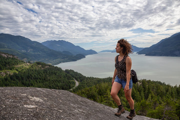 Naklejka premium Adventurous Girl Hiking up a mountain during a vibrant summer day. Taken in Murrin Park near Squamish, North of Vancouver, BC, Canada.