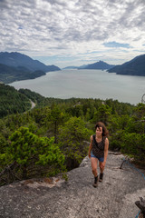 Naklejka premium Adventurous Girl Hiking up a mountain during a vibrant summer day. Taken in Murrin Park near Squamish, North of Vancouver, BC, Canada.