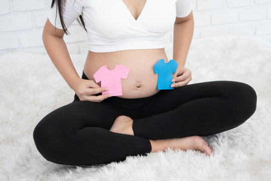 Pregnant Asian woman smiling and happy to be mom and imagine her child will be boy or girl. Baby gender prediction by ultrasound technology. .Pregnancy care and lifestyle or baby shower concept.