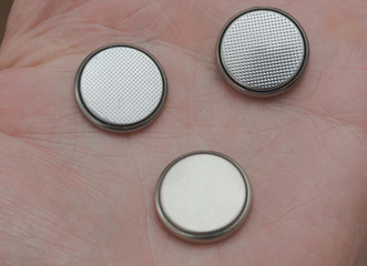 three round batteries lie on the palm of a person