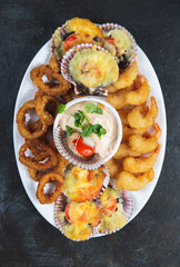 PERUVIAN FOOD. Piqueo caliente. Hot seafood platter fried shrimps, squid rings and baked scallops with sauce 