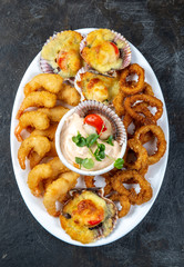 PERUVIAN FOOD. Piqueo caliente. Hot seafood platter fried shrimps, squid rings and baked scallops with sauce