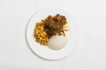 Delicious dish of Peruvian food " cabrito" on white textured background