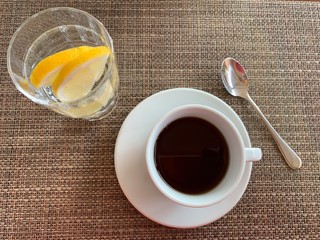 Glass of water with lemon and cup of tea