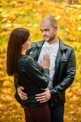 Portrait. Autumn forest. Yellow autumn background.A pair of dark-haired girl and a bald brutal man...