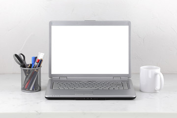 Laptop on marble office desk coffee mug and pens. White screen template with clipping path