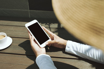 Mockup image of hand holding mobile phone with blank black screen in vintage cafe outside