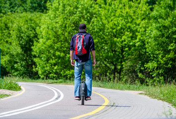 Guy rides unicycle scooter for city Park. 