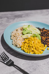 vegan mexican style dish with spicy black bean coconut rice corn and avocado