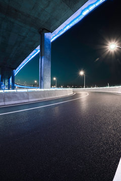 Empty road floor with city viaduct bridge of neon lights night