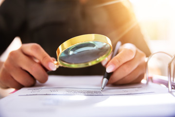 Human Hand Holding Magnifying Glass Over Invoice