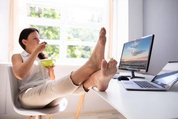 Businesswoman Watching Video On Computer And Eating Food