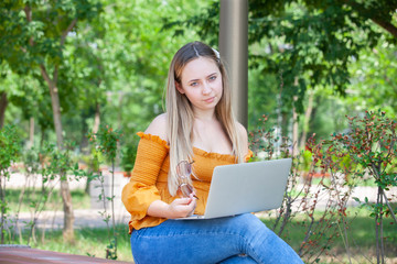 Young woman with laptop on green grass at park