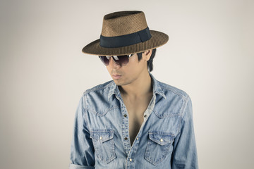 Fototapeta premium Portrait Man in Jeans Shirt Wear Eyeglasses and Hat Looking Below in Vintage Tone
