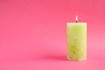 Alight wax candle on color background. Space for text