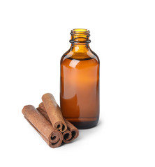 Bottle of essential oil and cinnamon sticks on white background