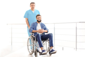 Male doctor taking care of man in wheelchair indoors