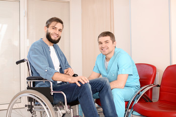 Male doctor taking care of man in wheelchair indoors