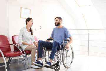 Young female doctor taking care of man in wheelchair indoors