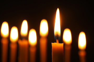 Burning candles on dark background, space for text. Symbol of sorrow