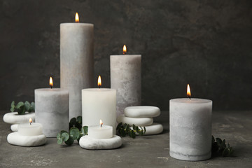 Composition with burning candles, spa stones and eucalyptus on grey table