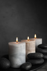 Burning candles and spa stones on black plate, space for text