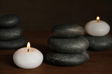 Fototapeta na wymiar Burning candles and spa stones on wooden table