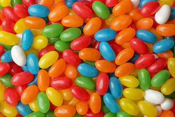 Tasty bright jelly beans as background, top view