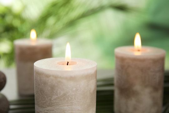 Burning aromatic candles on blurred green background