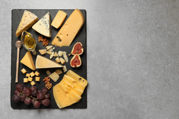 Different delicious cheeses served on grey table, top view. Space for text