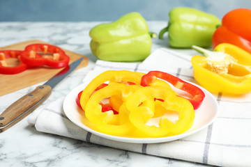 Plate with cut ripe bell peppers on marble table