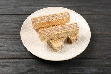Plate with delicious crispy wafers on wooden table