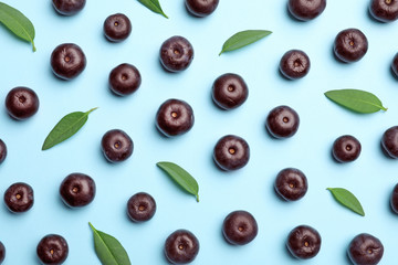 Fresh acai berries with leaves on blue background, flat lay