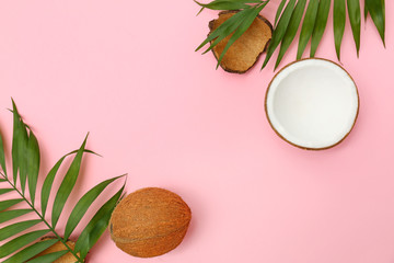 Fototapeta na wymiar Fresh coconuts and palm leaves on pink background, flat lay. Space for text